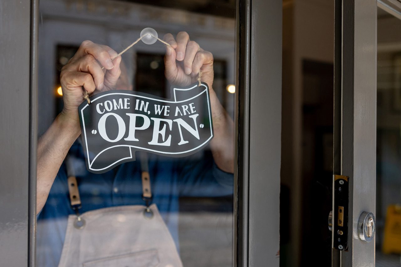 Close-up-on-a-business-owner-hanging-an-open-sign-on-the-door