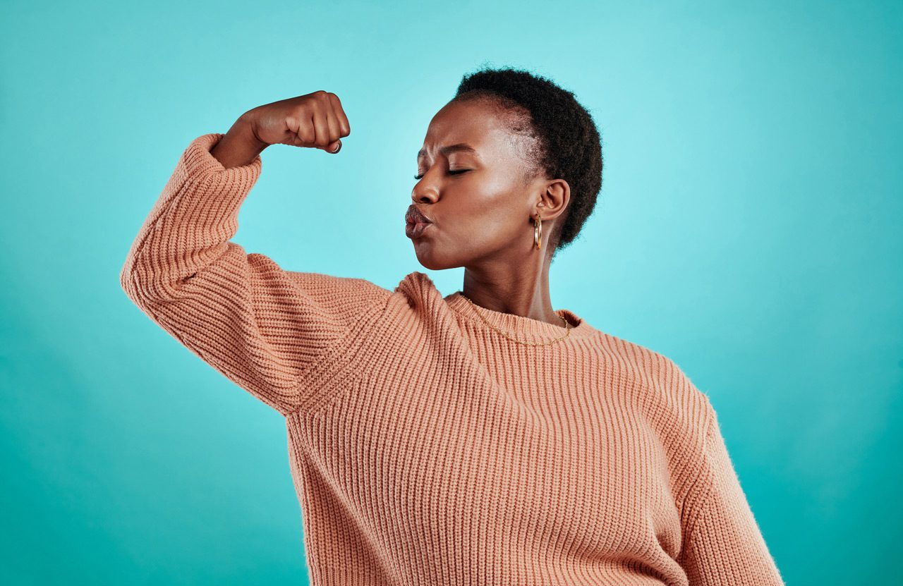 Shot-of-a-beautiful-young-woman-flexing-while-standing-against-a-turquoise-background